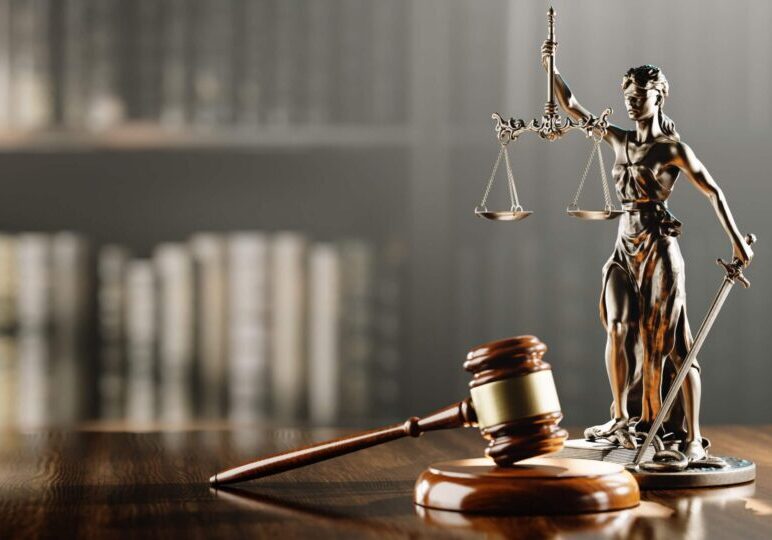 Gavel and Lady Justice statue on table.