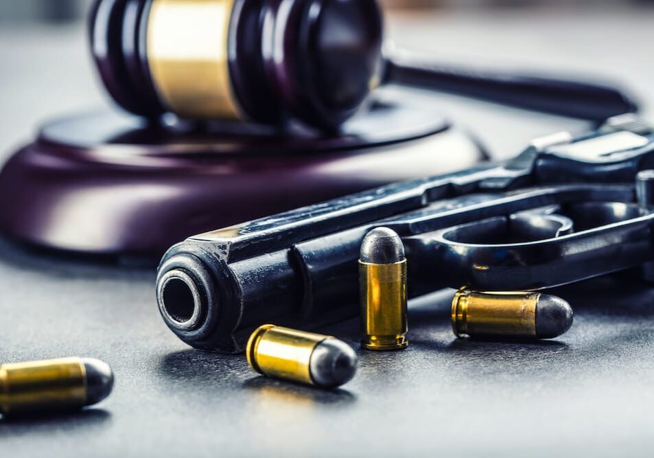 Gavel and gun with bullets on table.