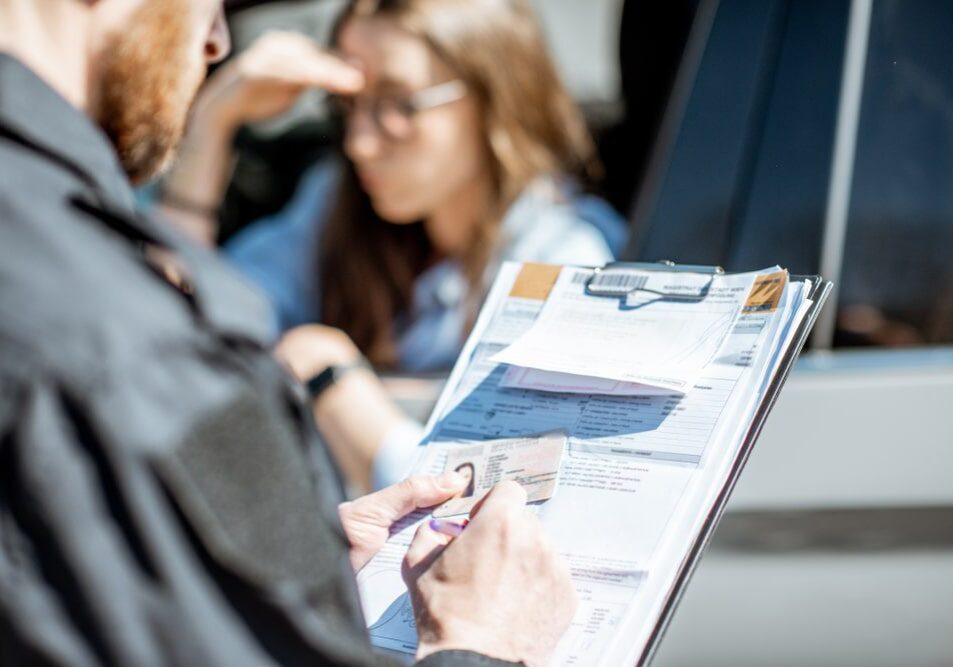 Police officer reviewing driver's license and documents.