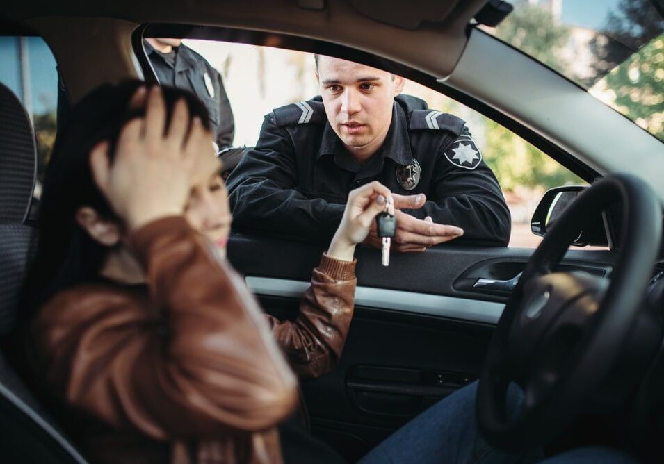 Police officer talking to driver in car.