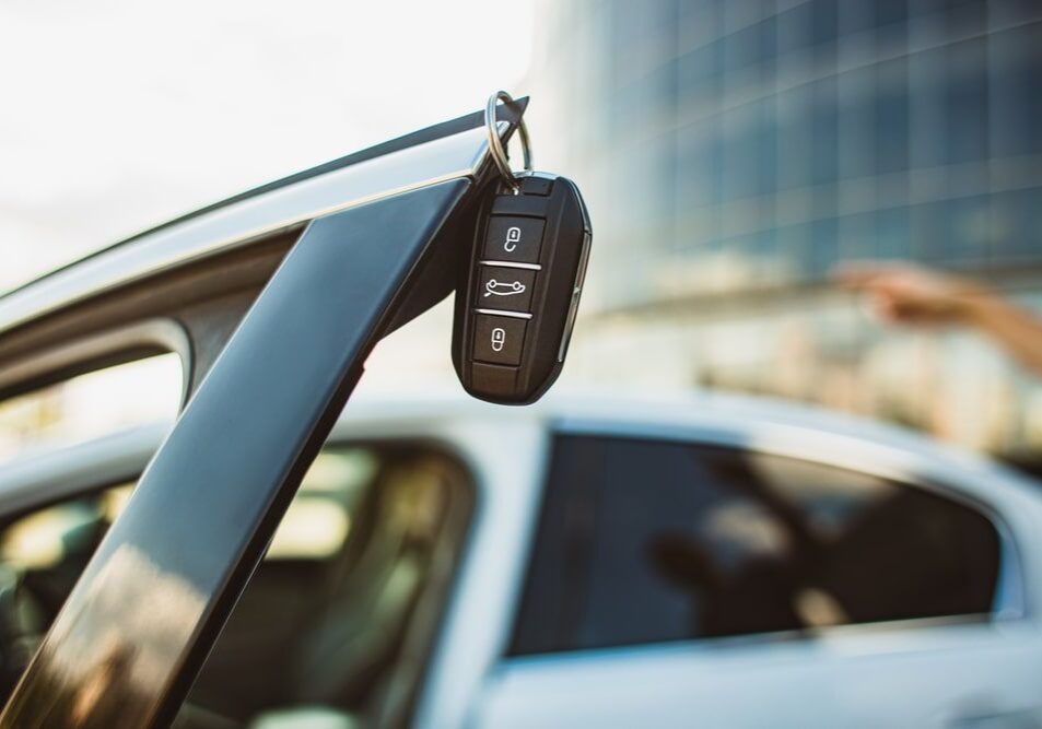 Car key hanging from vehicle door handle.