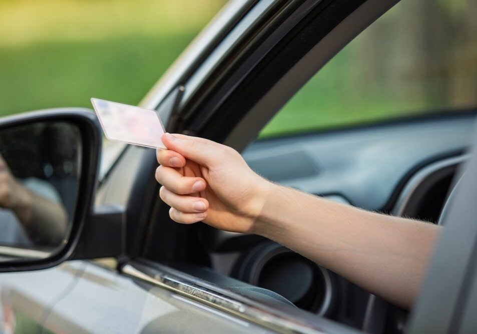 Hand holding card outside car window.