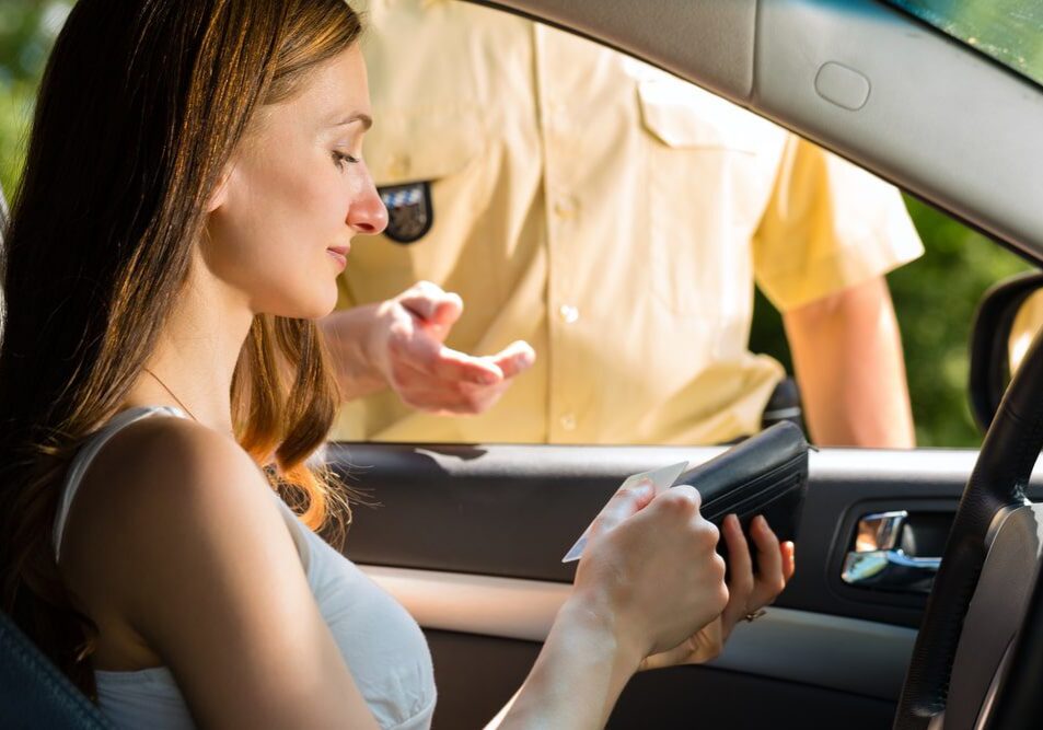 Woman in car showing ID to officer.