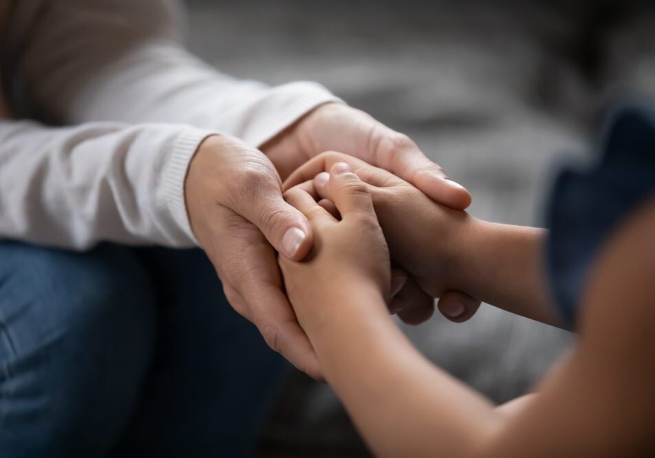 Adult and child holding hands, showing care.