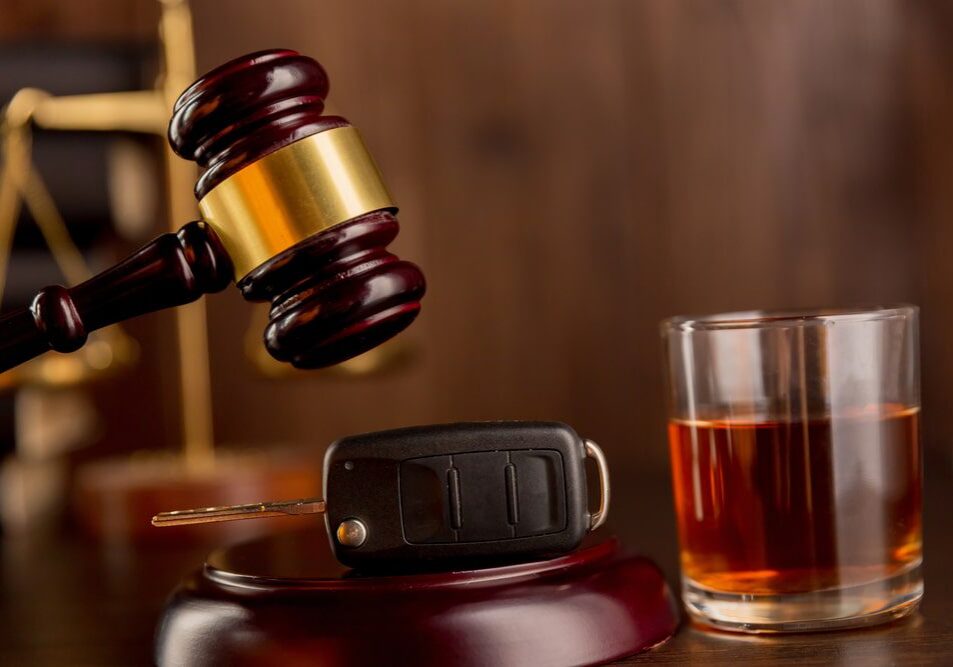 Gavel, car key, and drink on table.