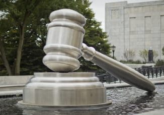 Large gavel sculpture outside a building.