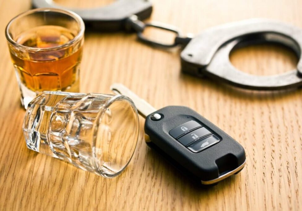 Car key, handcuffs, and whiskey glass.