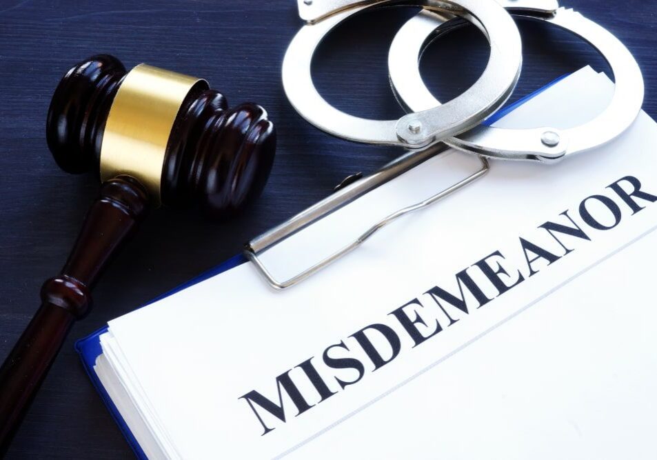 Gavel, handcuffs, and misdemeanor document on table.
