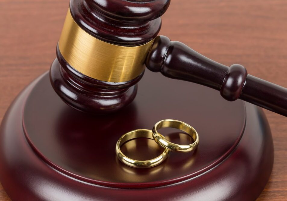 Gavel and wedding rings on wooden surface.